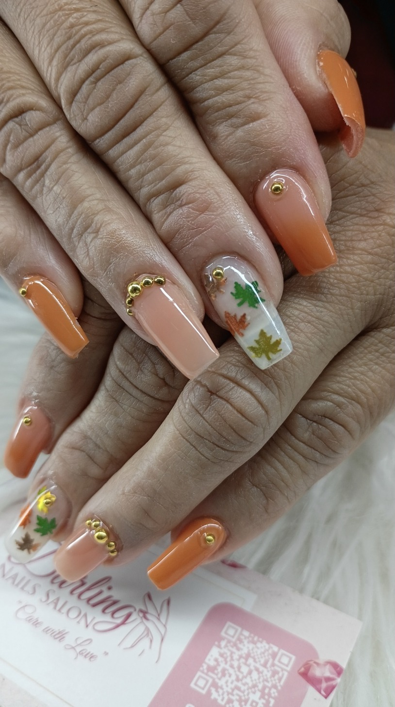 Close-up of an autumn manicure with orange accents and leaf designs