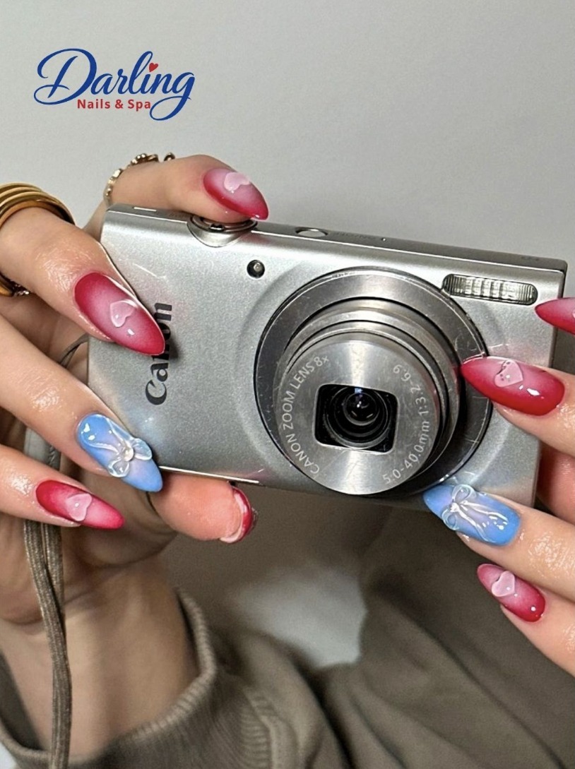Colorful decorated nails holding a silver camera